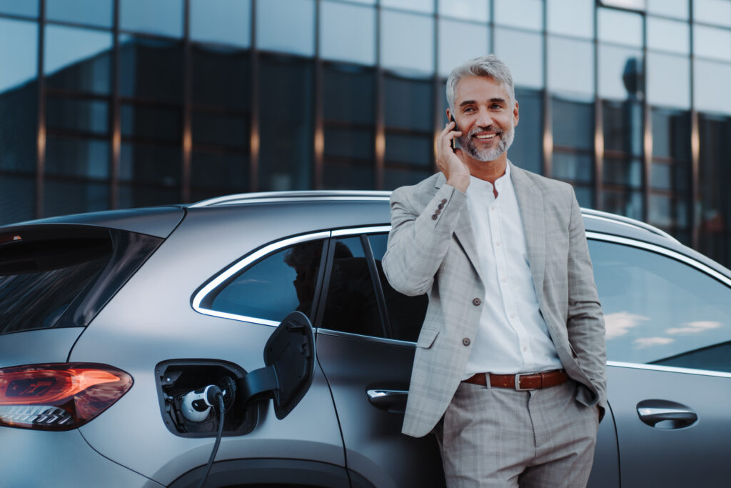 businessman talking on the phone while electric vehicle charges